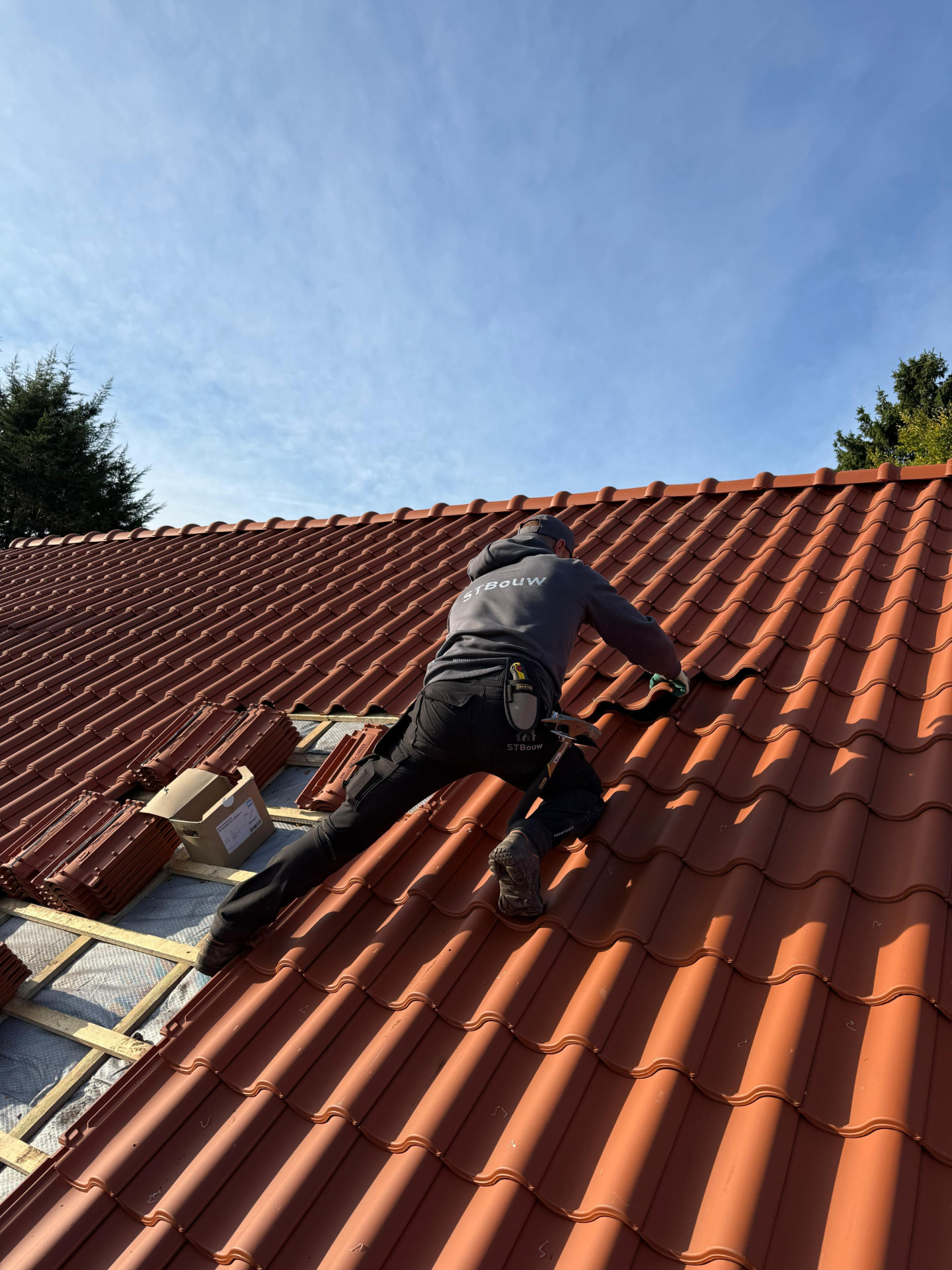 Vakman van STbouw in hoodie aan het werk op het dak