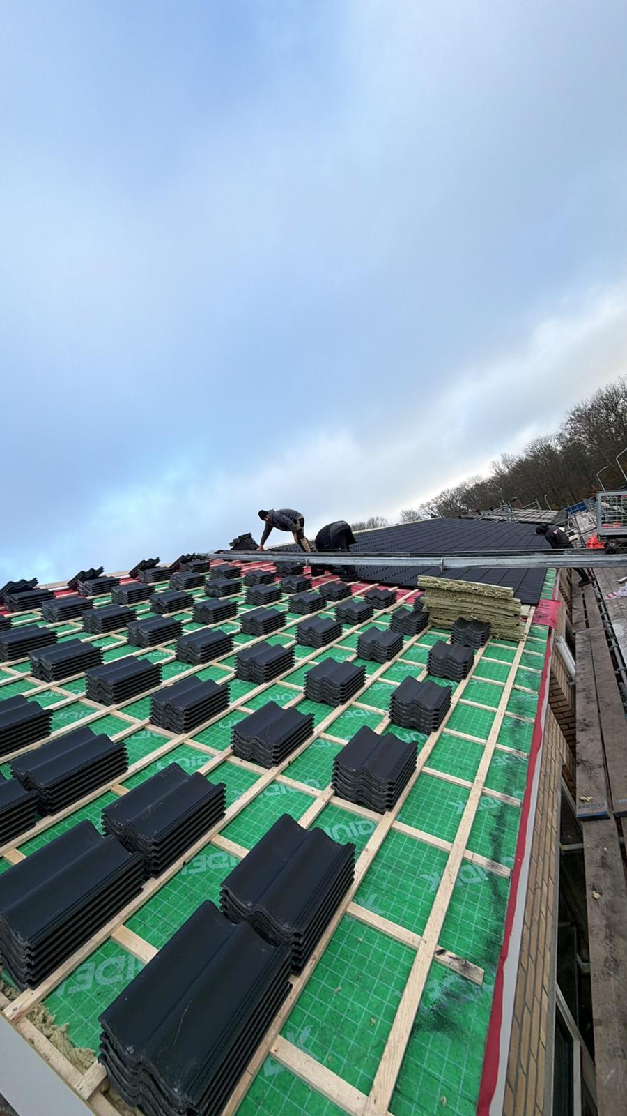 Nieuwe pannen gestapeld op folie en panlatten