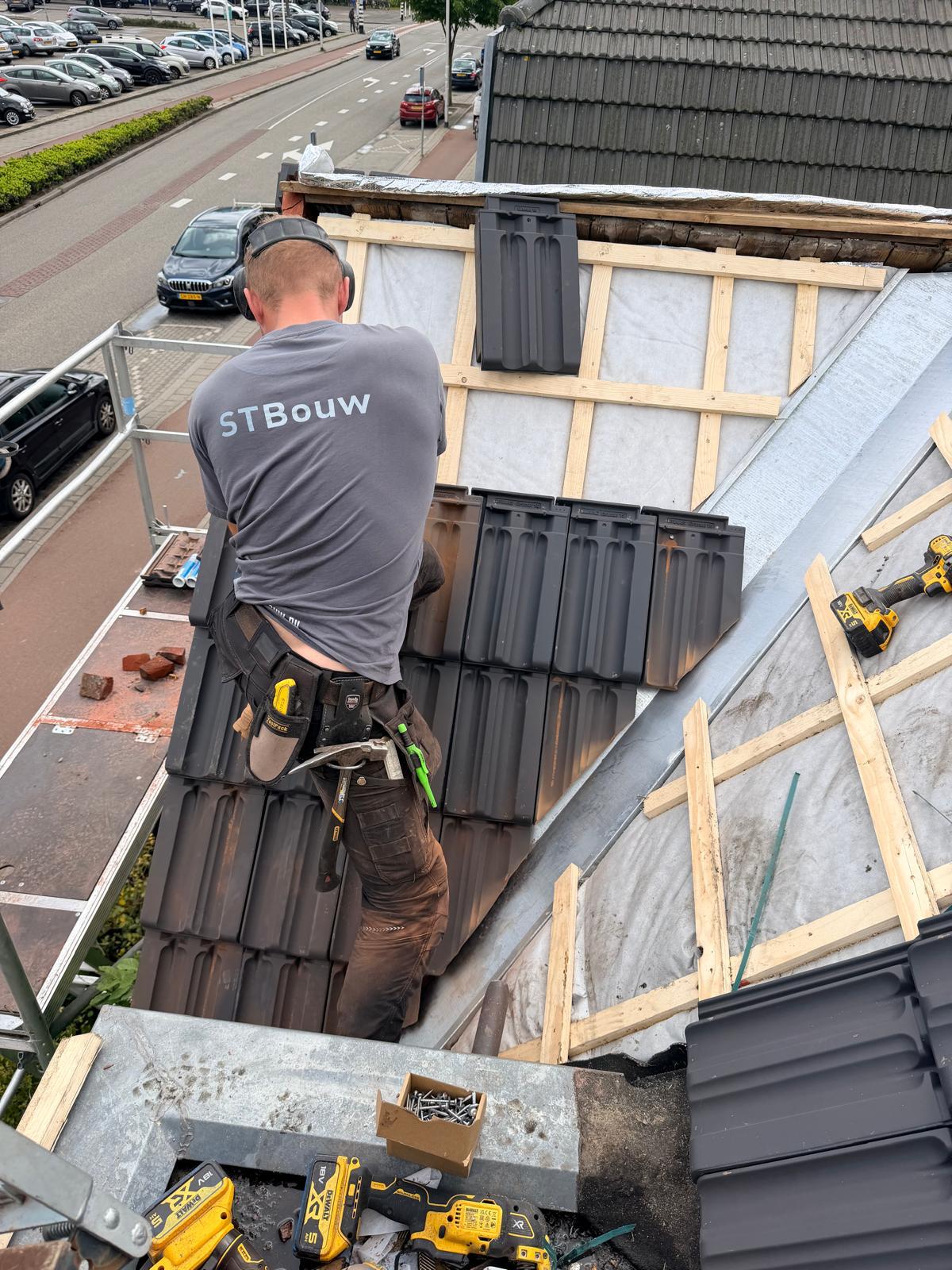 Vakman van STbouw legt nieuwe dakpannen