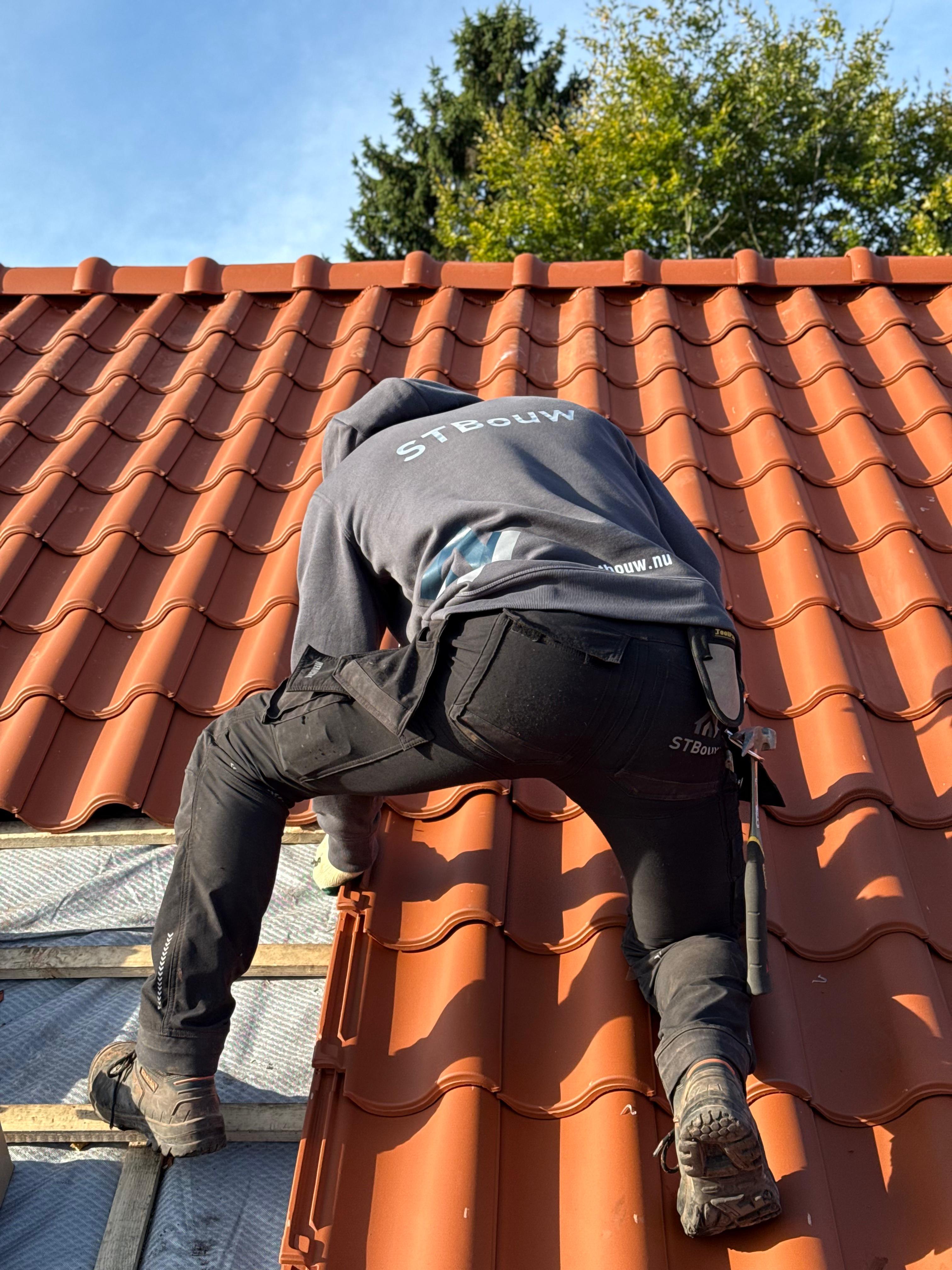 Vakman van STbouw in hoodie aan het werk op een pannendak